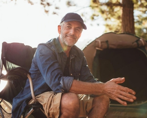 Man at campsite smiling with tent in background
