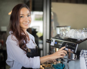 Barista looking at camera smiling while making a drink