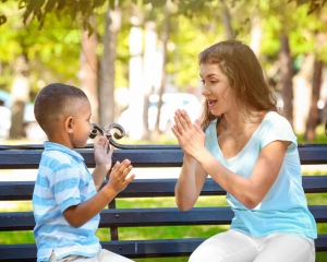 Woman and child playing pattycake on a park bench