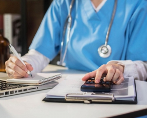 Nurse doing paperwork while using calculator