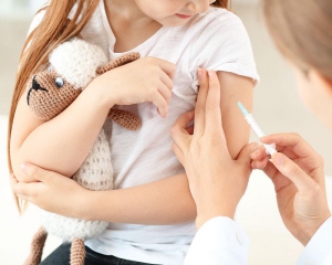 Child receiving a vaccine while holding stuffed animal