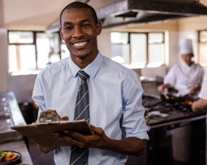 Food manager smiling at camera with clipboard