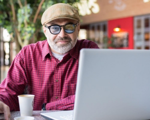 Older man with laptop looking at camera
